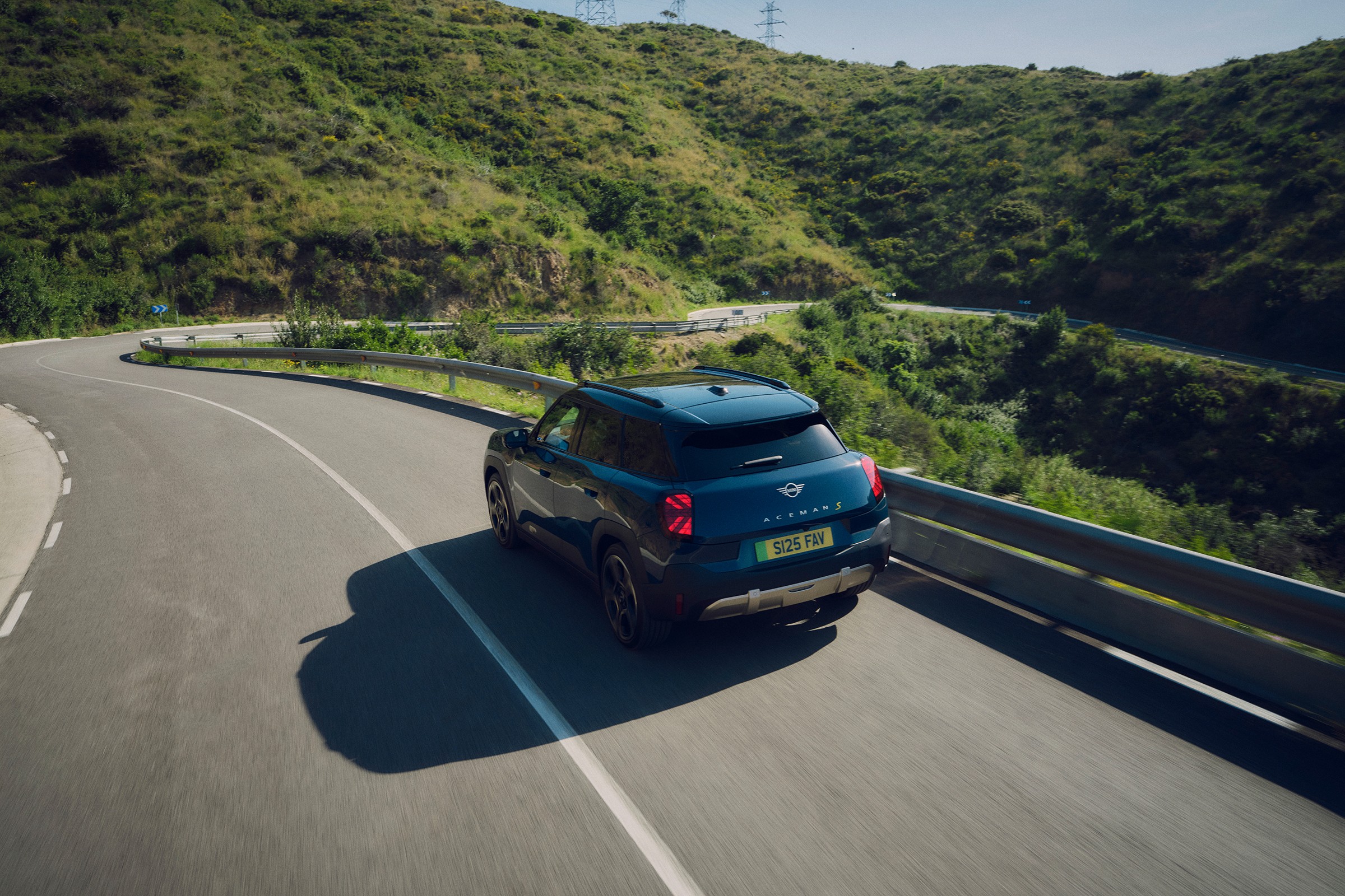 Mini Aceman Elétrico a circular na estrada, rodeado por paisagem natural 